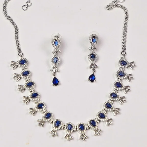 Diamond necklace and earring set with blue gemstones on a white background.