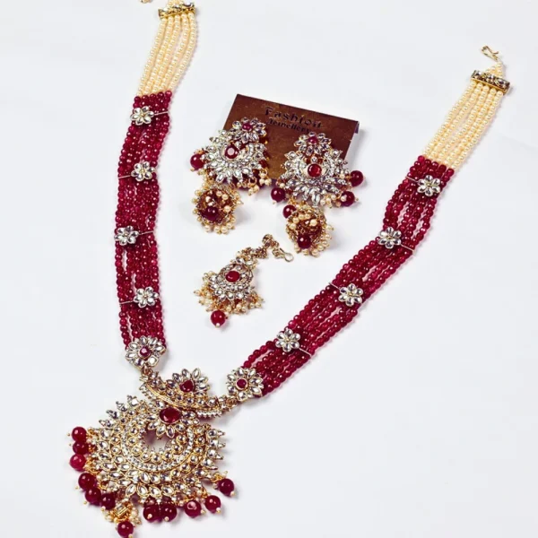 Long tailed red and gold beaded necklace set with matching earrings and mang tikka on a white background.