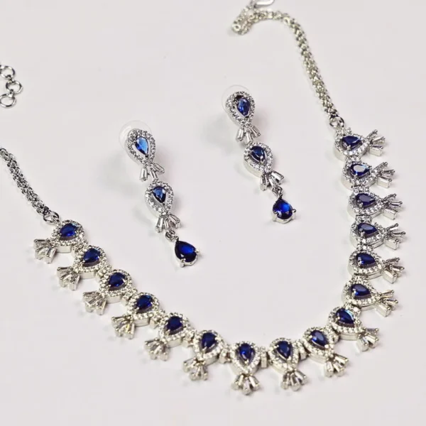 Diamond necklace and earring set with blue gemstones on a white background.