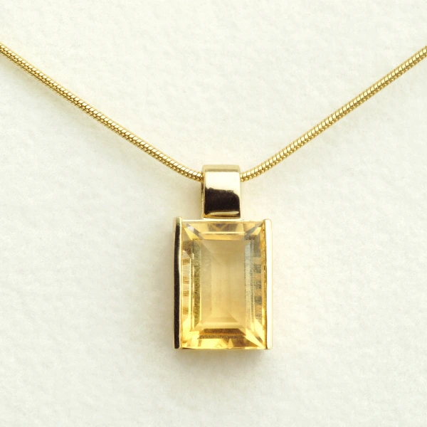 Gold necklace with a large rectangular yellow gemstone pendant.