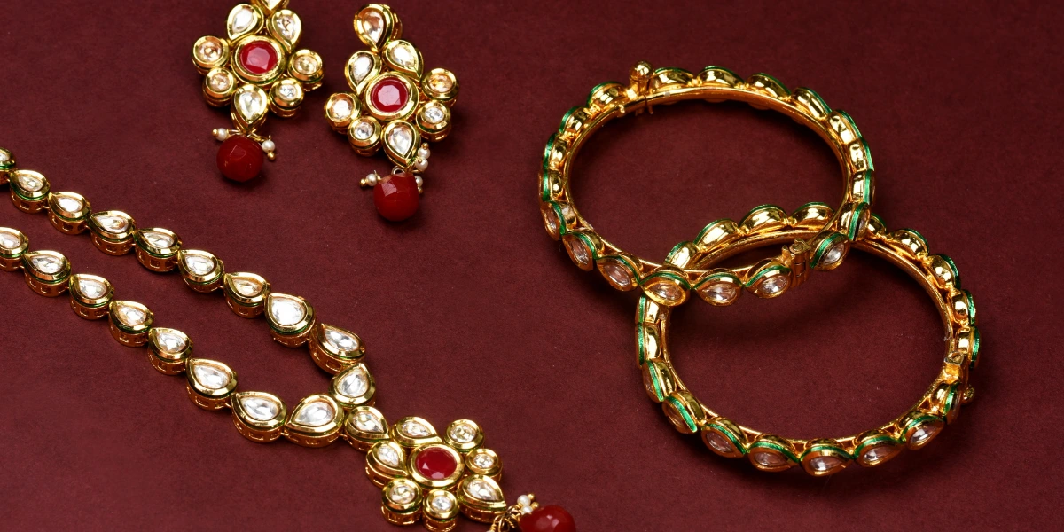 Gold traditional jewelry with Polki work on maroon background.