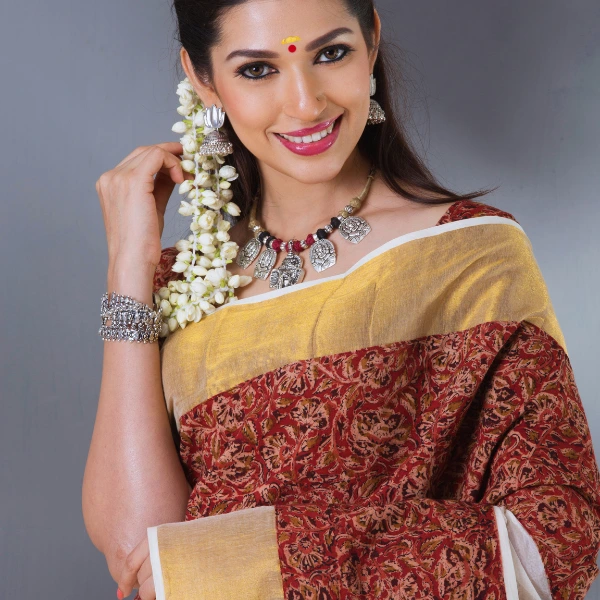 Woman in traditional saree with jasmine flowers and silver jewelry.