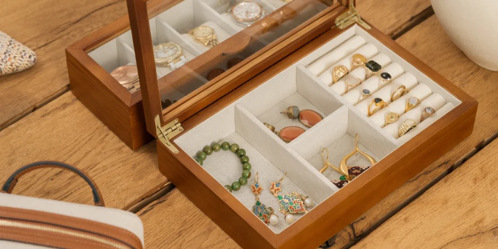 Wooden jewelry box with various pieces of jewelry displayed on a table.