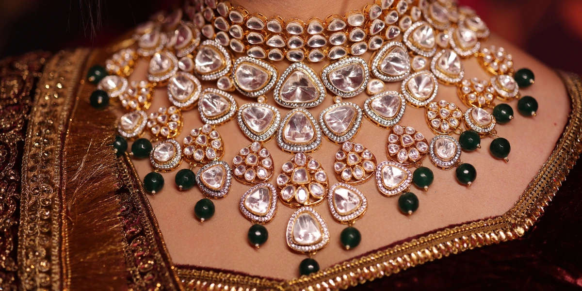 A stunning Kundan diamond and emerald necklace paired with a red and gold outfit, showcasing timeless elegance.
