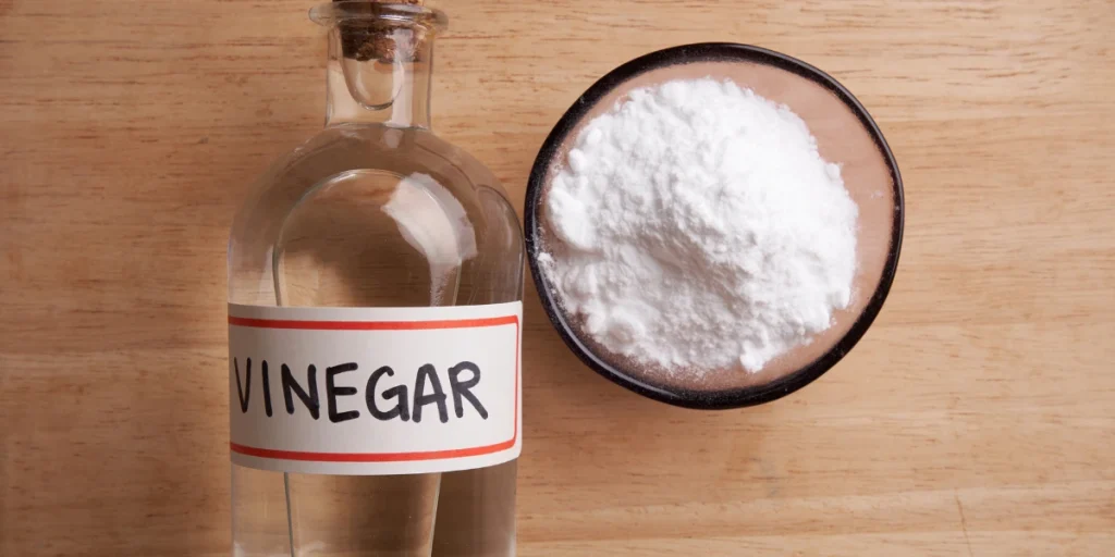 How to clean oxidised jewellery bottle of vinegar next to a bowl of white powder on a wooden surface.