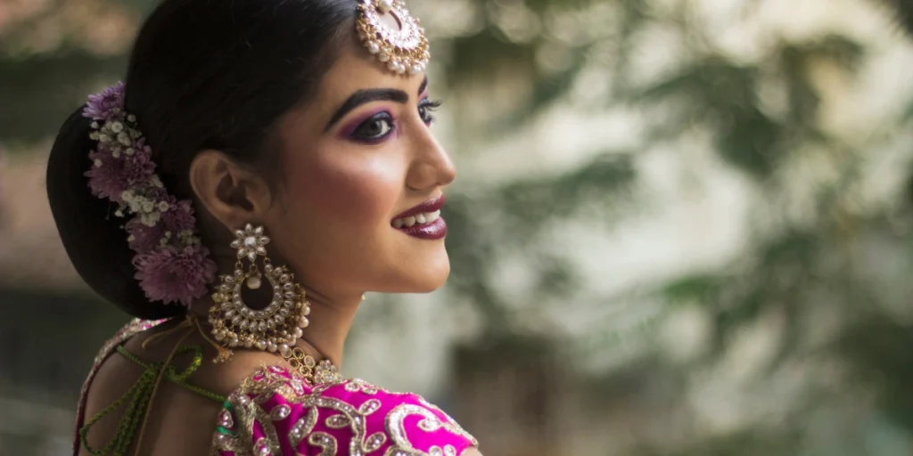 A woman in a vibrant pink traditional outfit thinking what jewellery to wear with lehenga