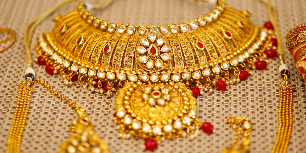 A close-up of antique temple jewellery showcasing a detailed necklace with pearl and red stone accents, alongside matching pieces.